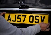 A man using sticky pads to fix number plate of his Mercedez