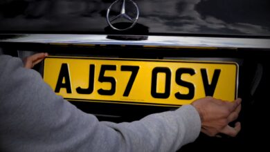 A man using sticky pads to fix number plate of his Mercedez