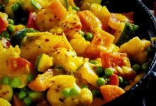 A pan of vegetable curry with a colorful mix of vegetables and potatoes